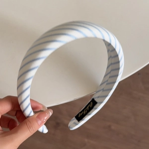 Detail view of the thick blue and white striped fabric headband with a luxury inner label