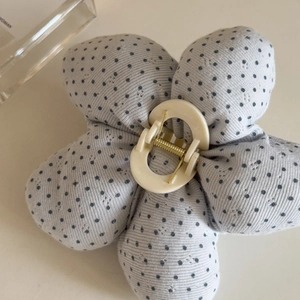 Close-up of a floral hair claw clip in grey-blue polka dot fabric with metal spring