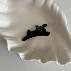 Macro detail of black dog acetate hair clip with golden facial accents on shell tray