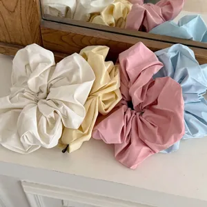 Set of four oversized cream-colored faux leather scrunchies in soft macaron shades