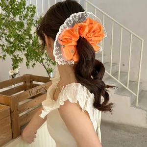 Orange floral scrunchie with lace trim worn on a ponytail for a fresh, sweet style