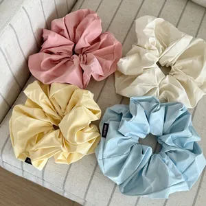 Set of four pastel satin hair scrunchies with Hand Made label on fabric background