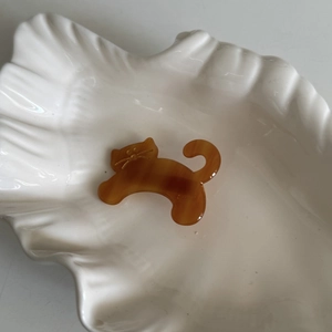 Detailed macro view of an amber acetate cat-shaped hair clip on a white shell tray