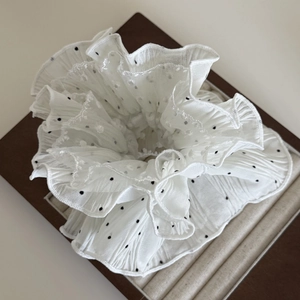 White polka dot lace scrunchie with layered ruffle design on a dark jewelry tray