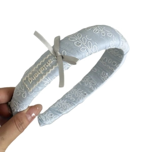Serre-tête rembourré en tissu bleu clair avec broderie blanche et nœud en ruban gris