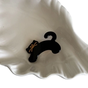 Cute black cat acetate hair clip with golden facial details on white ceramic plate