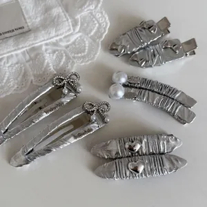 Dettaglio dei fermagli per capelli in argento con perle e cuori stile Y2K trendy
