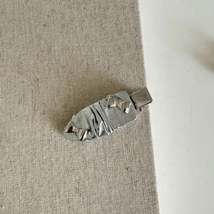 Dettaglio della molletta per capelli a fiocco in pelle argento con accenti metallici lucidi
