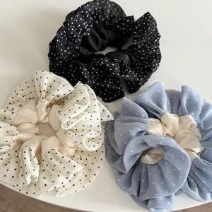Detailed macro view of three polka dot chiffon scrunchies in black, cream, and light blue