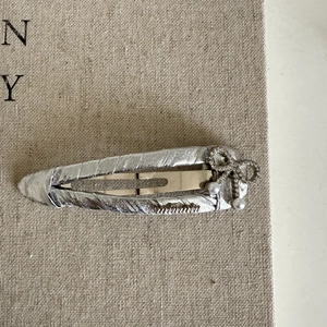 Fermaglio per capelli in pelle argento con fiocco, perle e strass su tela beige