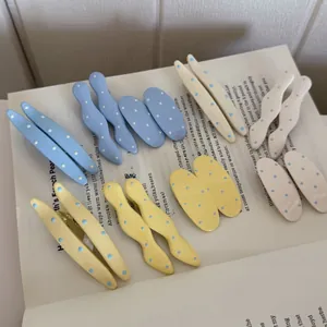 Close-up of cream polka dot hair clips in blue and yellow on vintage book pages