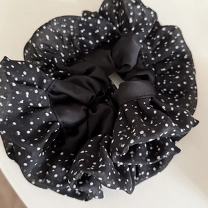 Chic black scrunchie featuring white polka dot sheer lace detail and pleated fabric design