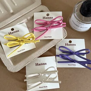 Elegant leather bow hair clips in multiple pastel colors on a minimalist display card