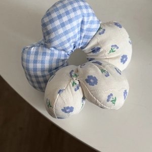 Gros plan d'un chouchou en tissu floral bleu et à carreaux, texture coton doux