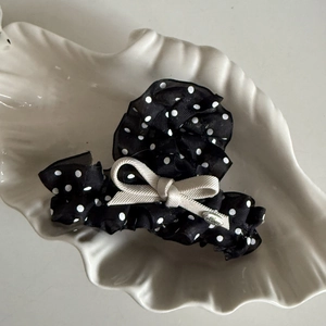 Detailed shot of black polka dot hair claw with a cream ribbon bow and heart charm