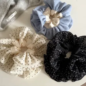 Polka dot lace scrunchies in blue and cream colors on a soft knit hat background