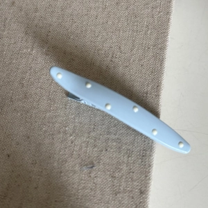 Detail of light blue polka dot hair clip on rustic beige fabric background