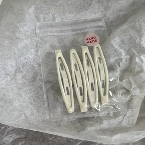 Gros plan de quatre barrettes goutte jaune crème dans un sachet avec autocollant rose