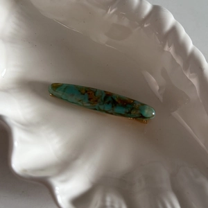 Barrette à cheveux élégante en acétate marbré vert avec base dorée sur plat coquillage