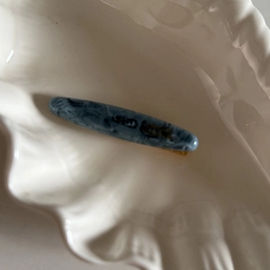 Détail d'une pince à cheveux en acétate motif marbre bleu gris sur plateau coquillage