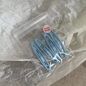 Vue détaillée de 4 barrettes bleues en métal émaillé avec étiquette fait main