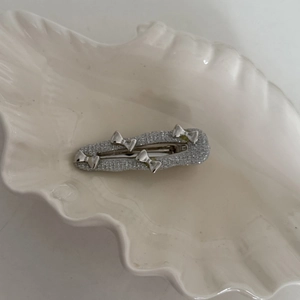 Sparkly silver glitter hair clip with metallic butterfly accents on a shell plate