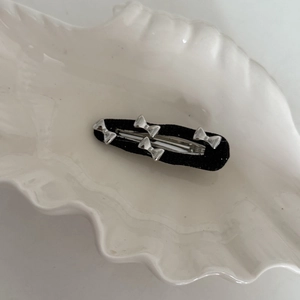 Elegant black fabric BB hair clip with silver mini metal bows on white shell tray