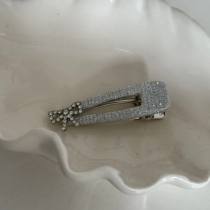 Detailed view of silver hair clip with rhinestones and bow on shell tray