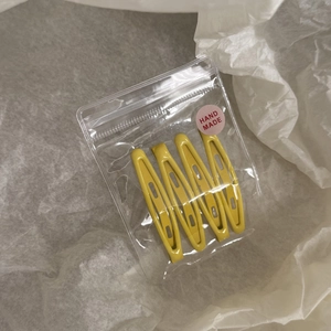 Lot de quatre barrettes BB en émail jaune dans un sachet zippé de style artisanal