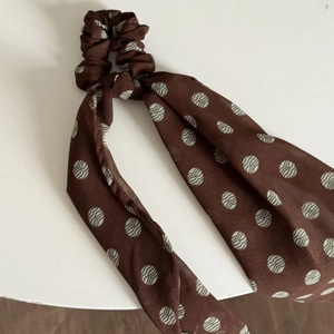 Detailed close-up of brown chiffon scrunchie with ribbons and green ripple patterns