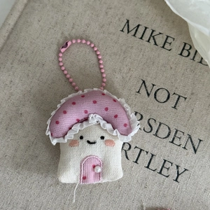 Detail of handmade fabric mushroom house charm with pink polka dots and lace trim