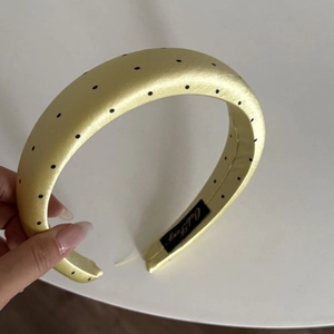 Detail of yellow satin polka dot padded headband featuring premium sponge texture