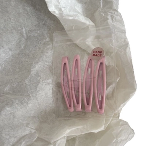 Lot de quatre barrettes à cheveux en métal rose dans un emballage fait main sur blanc