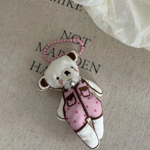 Detail of pink polka dot bear plush keychain with delicate lace bow and bead chain