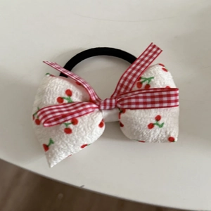 Detailansicht eines süßen Haargummis mit Kirschmuster, Spitze und kariertem Design