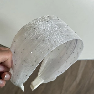 Detail of white wide headband with sparkling silver beads and pleated fabric texture