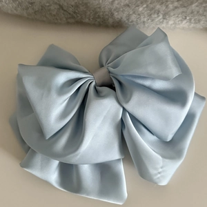 Détail d'une élégante pince à cheveux en satin bleu clair avec un nœud multicouche
