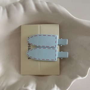 Detail view of light blue hair clips with pink stitch patterns on white shell plate