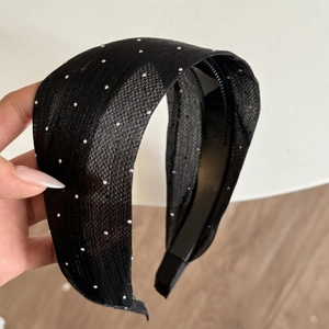 Close-up of wide black beaded headband with fabric texture and sparkling silver rhinestones