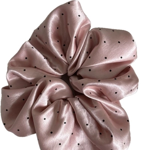 Pink satin scrunchie with black polka dots, soft hair accessory with a glossy finish