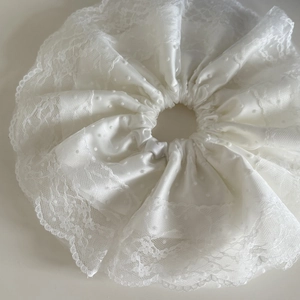 Nahaufnahme von weißem Seersucker Scrunchie mit Punkttextur und Spitze-Lagen