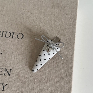 Dettaglio di un fermaglio per capelli a pois neri con fiocco e cuore d'argento