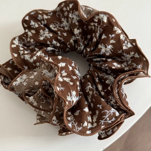 Gros plan détaillé d'un chouchou floral marron foncé avec bords en dentelle et texture