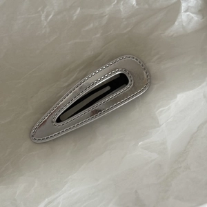 Minimalist shiny silver PU leather star and droplet BB hair clip on a textured white background