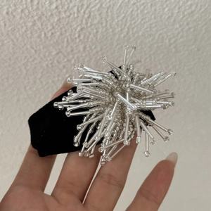 Détail d'une pince à cheveux perlée motif feu d'artifice avec base en velours noir