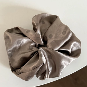 Close-up of champagne satin scrunchie with polka dots and high-quality silk texture