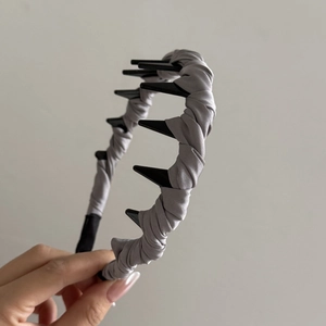 Dettaglio del cerchietto in raso grigio con denti antiscivolo in plastica nera