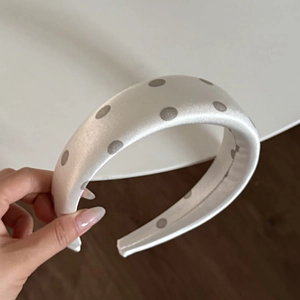 Detailed macro view of white satin headband with grey polka dots and thick padded design