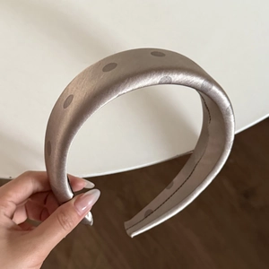 Detailed close-up of champagne satin headband with dark grey polka dots and thick texture
