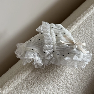 Detailed shot of white polka dot lace hair claw with ribbon bow and pearl pendant